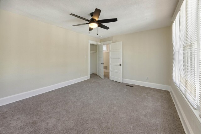 unfurnished bedroom with ceiling fan, carpet floors, and a textured ceiling