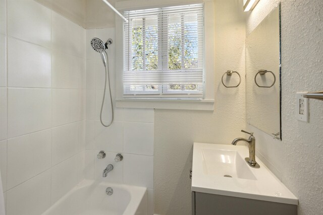 bathroom with vanity, tiled shower / bath, and a healthy amount of sunlight