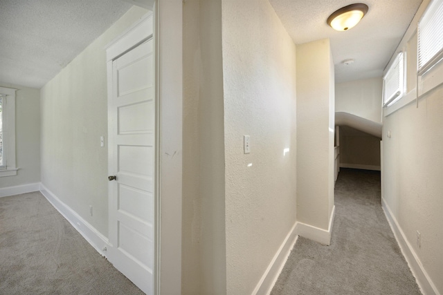 corridor featuring light colored carpet and a textured ceiling