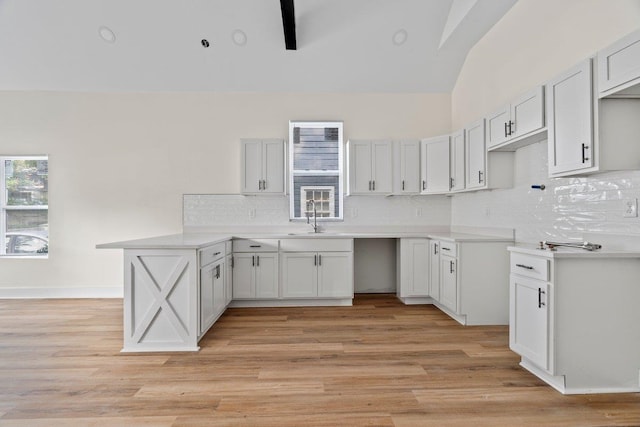 kitchen featuring decorative backsplash, sink, white cabinets, and light hardwood / wood-style floors