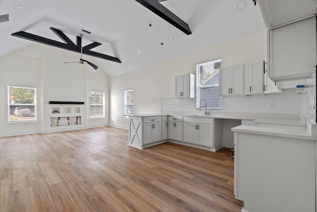 kitchen featuring beam ceiling, ceiling fan, white cabinets, and light wood-type flooring