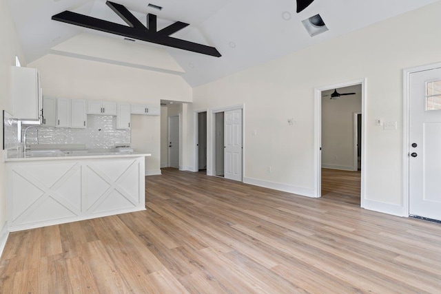 unfurnished living room featuring ceiling fan, light wood-type flooring, and sink