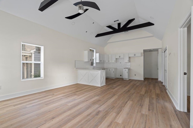 unfurnished living room with light hardwood / wood-style floors, high vaulted ceiling, ceiling fan, and sink