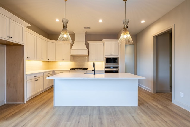 kitchen with premium range hood, appliances with stainless steel finishes, hanging light fixtures, and sink