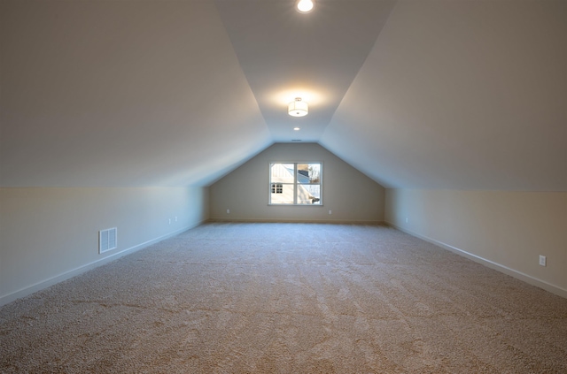 bonus room with vaulted ceiling and light carpet