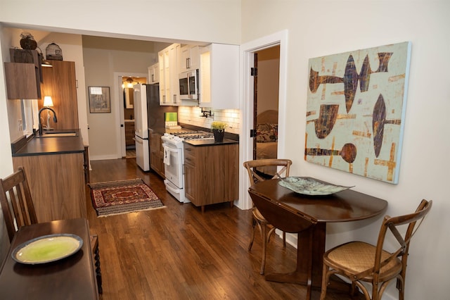 kitchen with sink, decorative backsplash, appliances with stainless steel finishes, dark hardwood / wood-style flooring, and white cabinetry