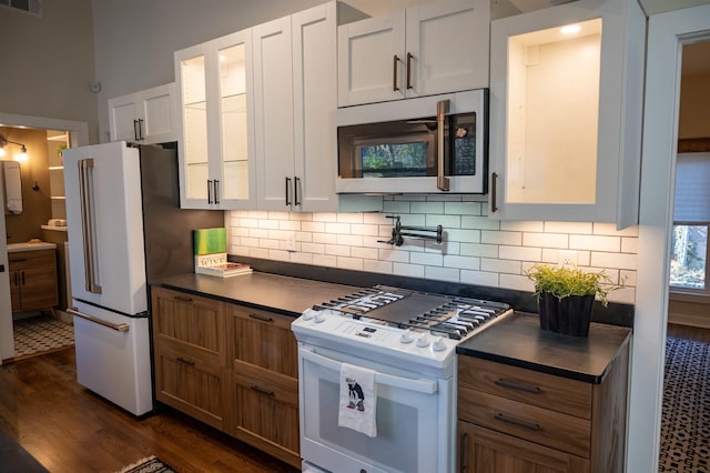 kitchen featuring white cabinets, decorative backsplash, white appliances, and dark hardwood / wood-style floors