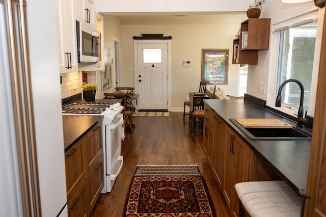 kitchen featuring white range with gas stovetop, decorative backsplash, dark hardwood / wood-style flooring, and sink