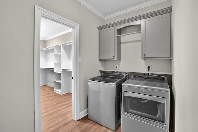 washroom featuring crown molding, washer and clothes dryer, cabinets, and light hardwood / wood-style floors