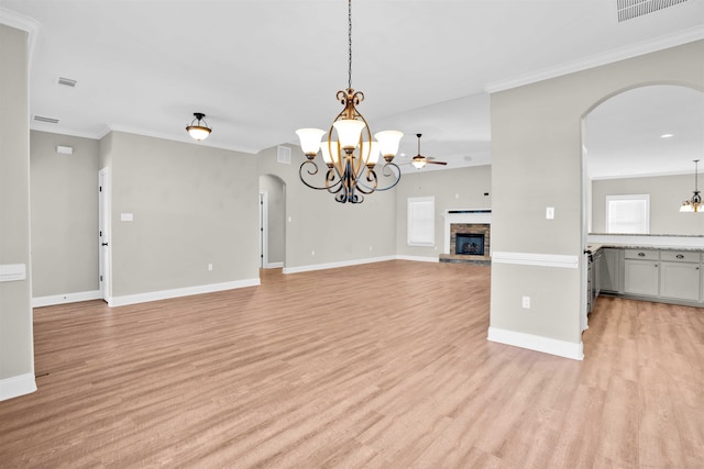 unfurnished living room with ceiling fan with notable chandelier, ornamental molding, a fireplace, and light hardwood / wood-style flooring