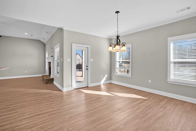 interior space with lofted ceiling, light hardwood / wood-style floors, ornamental molding, and a chandelier