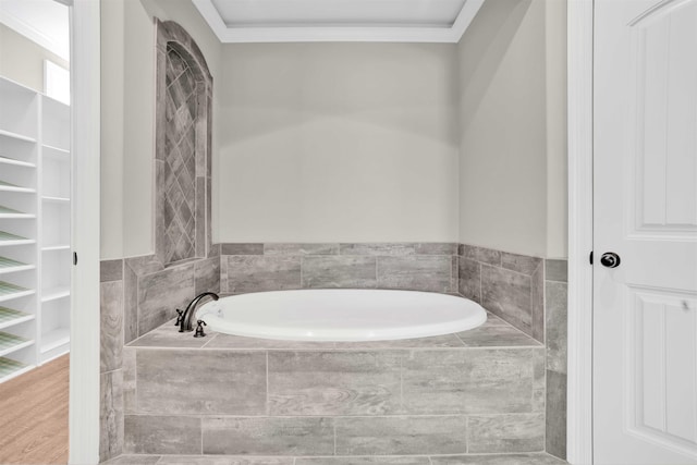 bathroom featuring tiled bath, hardwood / wood-style floors, and ornamental molding