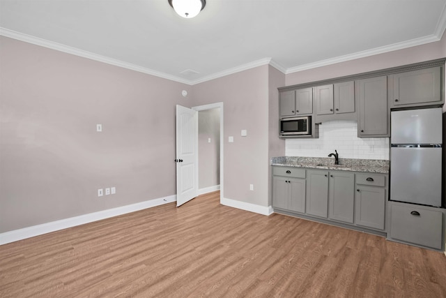 kitchen featuring decorative backsplash, sink, white refrigerator, light hardwood / wood-style flooring, and stainless steel microwave