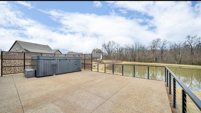 view of patio with a water view and a hot tub