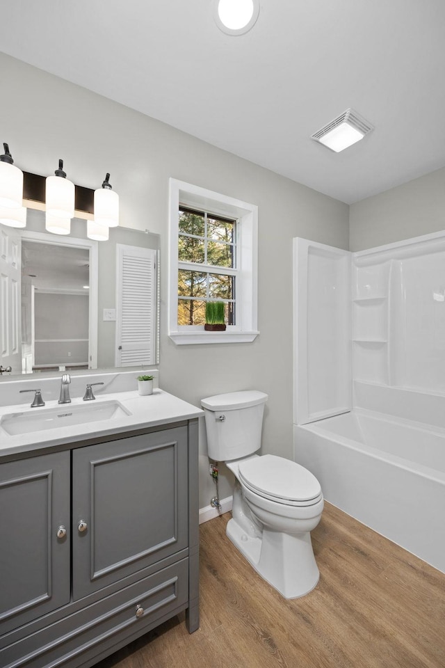 full bathroom with hardwood / wood-style floors, vanity, toilet, and shower / bathtub combination