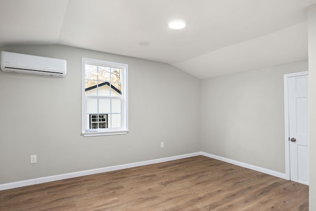 additional living space with a wall mounted air conditioner, dark wood-type flooring, and vaulted ceiling