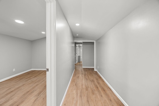 hall with light hardwood / wood-style floors and vaulted ceiling