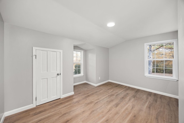 additional living space featuring plenty of natural light, vaulted ceiling, and light hardwood / wood-style flooring