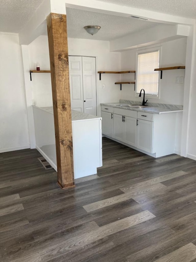 kitchen with a textured ceiling, sink, white cabinets, and dark hardwood / wood-style floors