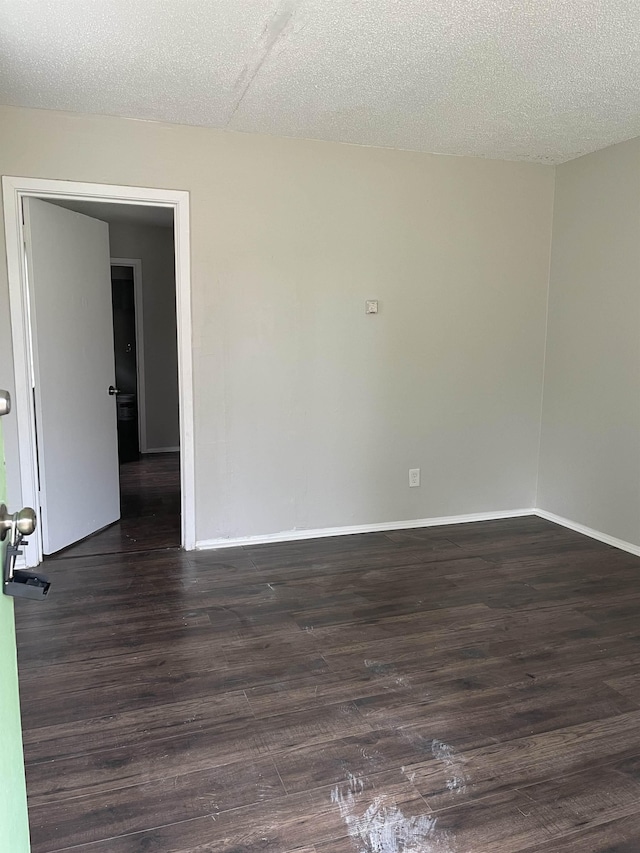 unfurnished room with dark wood-type flooring and a textured ceiling