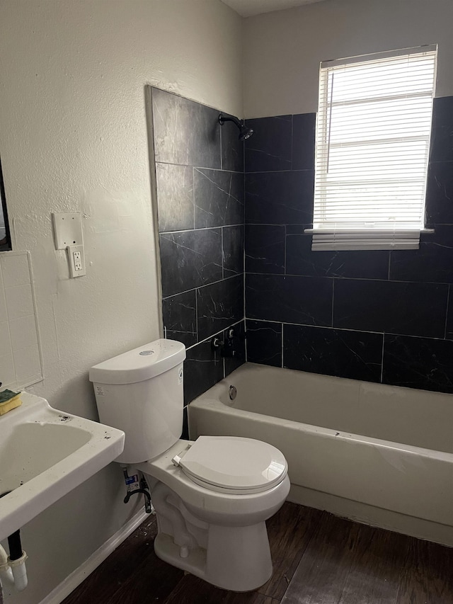 bathroom featuring hardwood / wood-style flooring, tiled shower / bath combo, and toilet