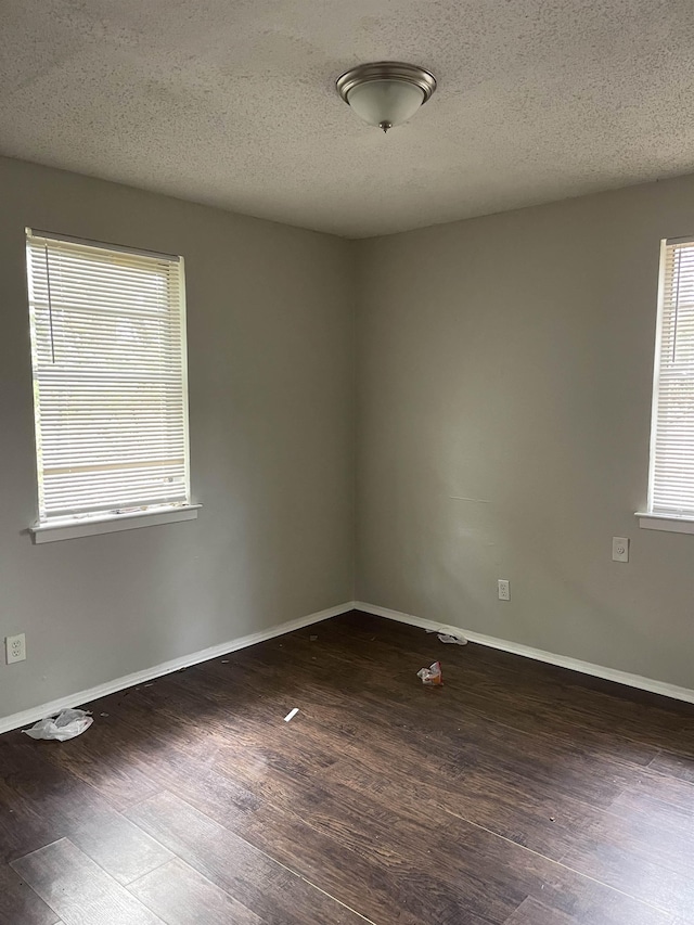 spare room with a textured ceiling and dark wood-type flooring