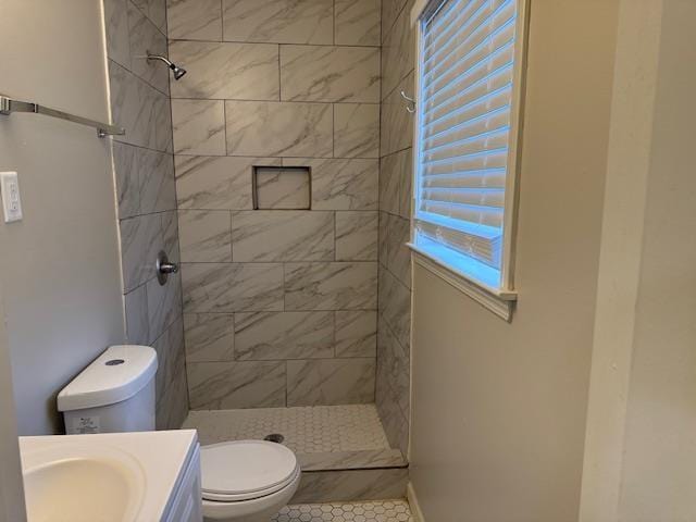 bathroom featuring tiled shower, tile patterned flooring, vanity, and toilet