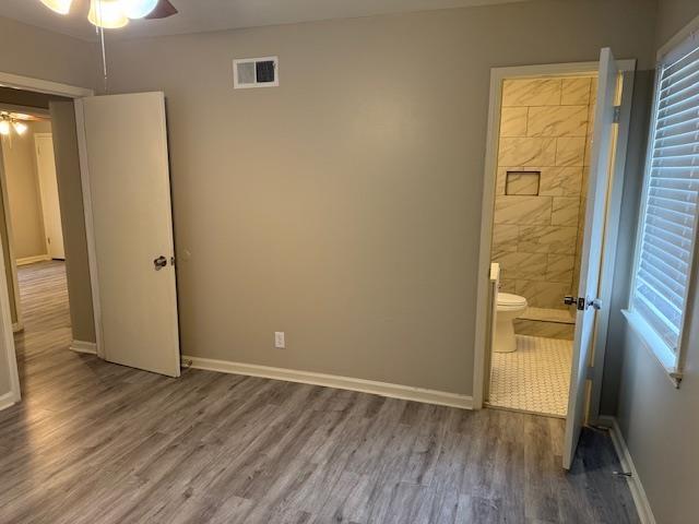 unfurnished bedroom featuring ensuite bathroom and wood-type flooring