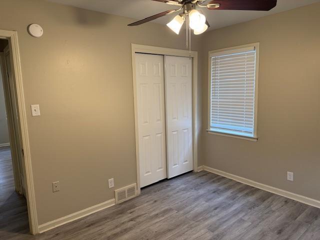 unfurnished bedroom with hardwood / wood-style floors, ceiling fan, and a closet