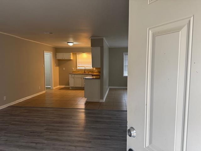 unfurnished living room with crown molding and dark wood-type flooring