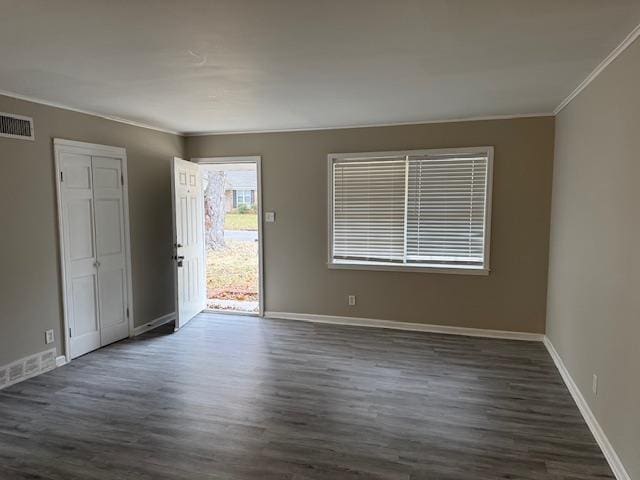 empty room featuring crown molding and dark wood-type flooring