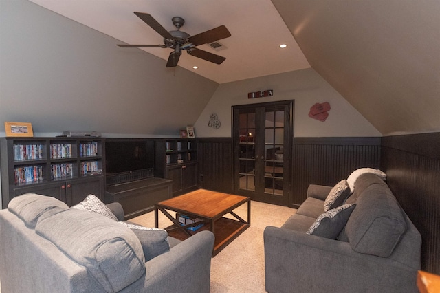 carpeted living room with french doors, vaulted ceiling, ceiling fan, and wooden walls