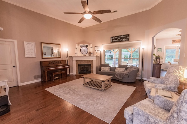 living room featuring a tiled fireplace, ceiling fan, dark hardwood / wood-style flooring, and ornamental molding