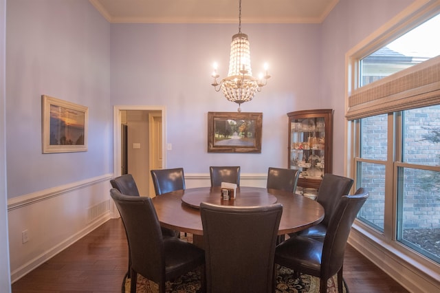 dining room featuring crown molding, dark wood-type flooring, and an inviting chandelier