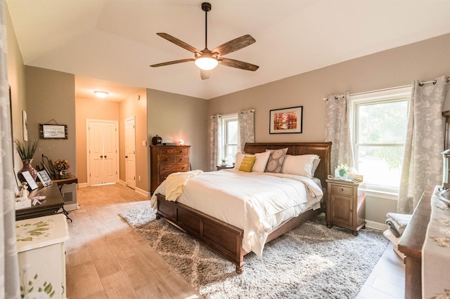 bedroom with light wood-type flooring, vaulted ceiling, and ceiling fan