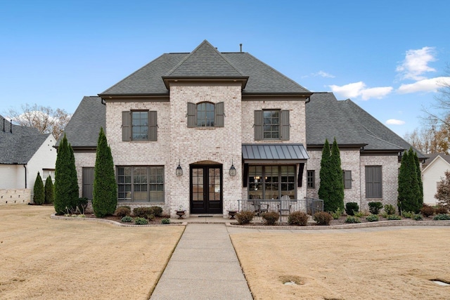 french country style house with a front yard, french doors, and a porch