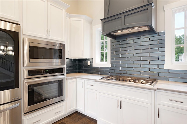 680 Magnolia Ln, Piperton, TN 38017 - kitchen with custom range hood, white gas cooktop, stainless steel microwave, light countertops, and tasteful backsplash