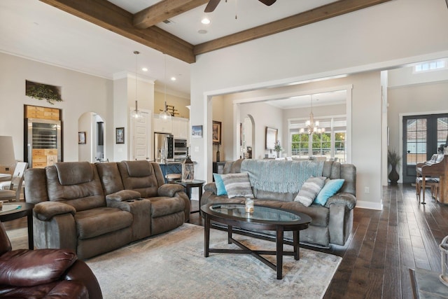 living room with beam ceiling, ceiling fan with notable chandelier, dark wood-type flooring, and a high ceiling