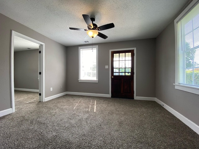 empty room with carpet flooring, ceiling fan, and a textured ceiling