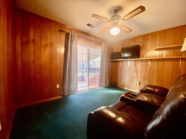 carpeted living room with ceiling fan and wood walls