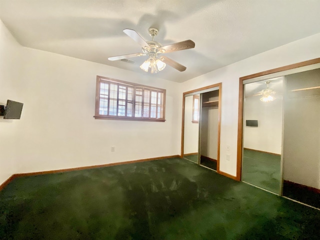 unfurnished bedroom featuring carpet flooring, ceiling fan, and two closets