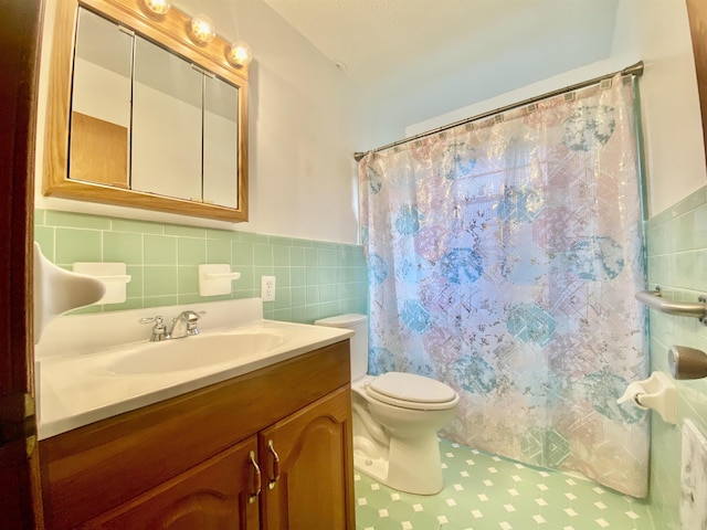 bathroom with a shower with curtain, tile patterned floors, toilet, vanity, and tile walls