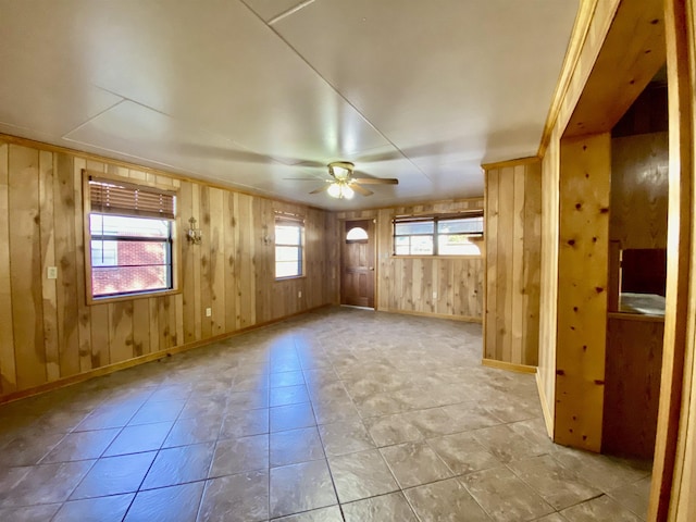 spare room with ceiling fan and wooden walls