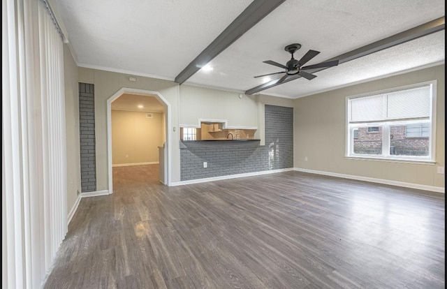 unfurnished living room featuring crown molding, dark hardwood / wood-style floors, ceiling fan, a textured ceiling, and beamed ceiling