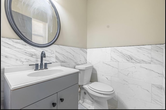 bathroom with vanity, tile walls, and toilet