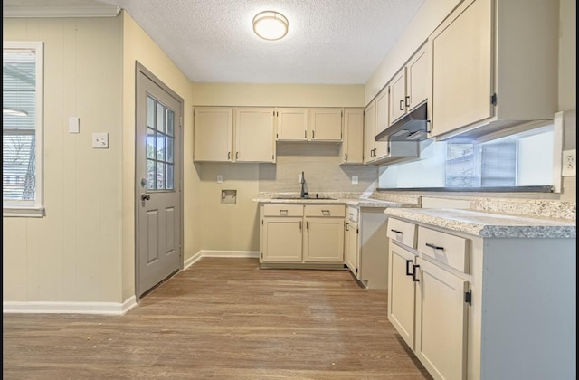 kitchen featuring a textured ceiling, light hardwood / wood-style flooring, wood walls, and sink