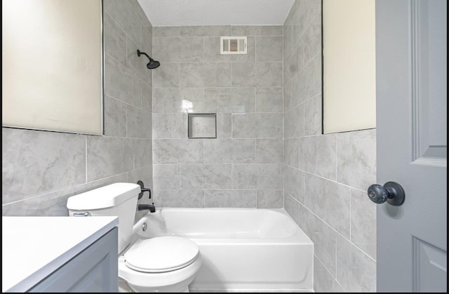 full bathroom with a textured ceiling, toilet, vanity, tile walls, and tiled shower / bath