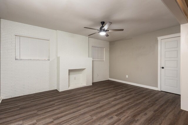 unfurnished living room with ceiling fan, dark hardwood / wood-style flooring, and brick wall