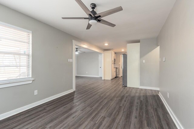 unfurnished living room featuring ceiling fan and dark wood-type flooring