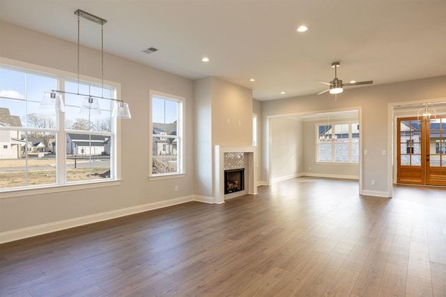 unfurnished living room with dark hardwood / wood-style flooring, a tile fireplace, and ceiling fan with notable chandelier